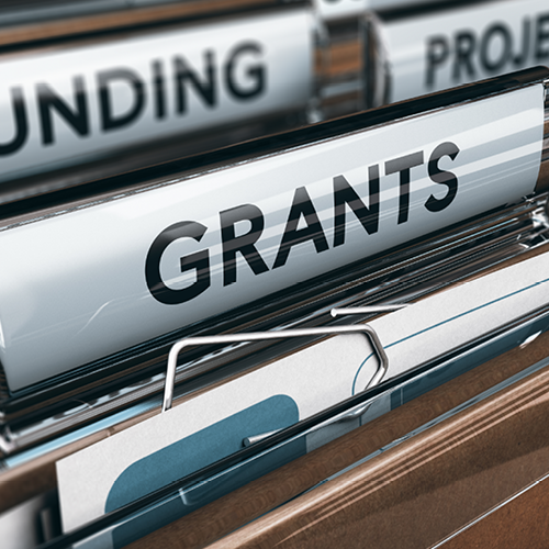 Close-up of labeled file folders, with ‘GRANTS’ in focus and ‘FUNDING’ visible in the background.