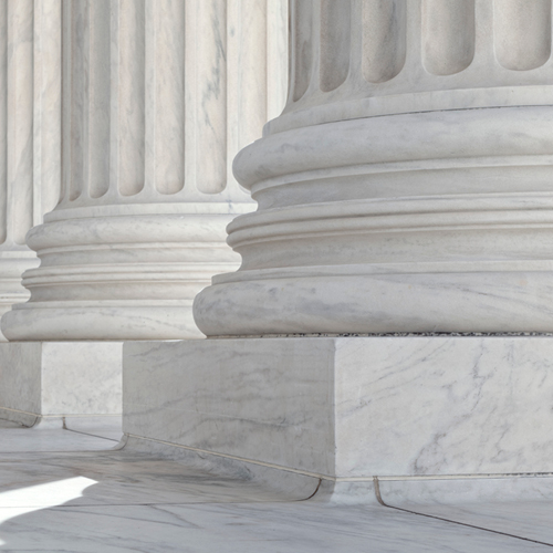 Close-up of large white marble columns with detailed bases and fluted shafts in a classical architectural setting.