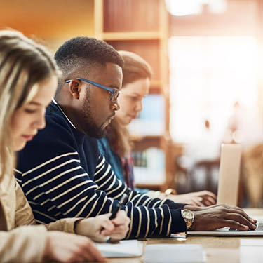 three students looking at their laptops