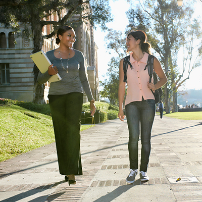 two students walking across a college campus, engaged in conversation