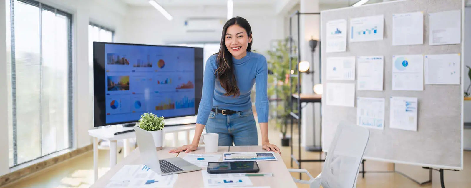 Female leaning over a desk with financial charts and computer
