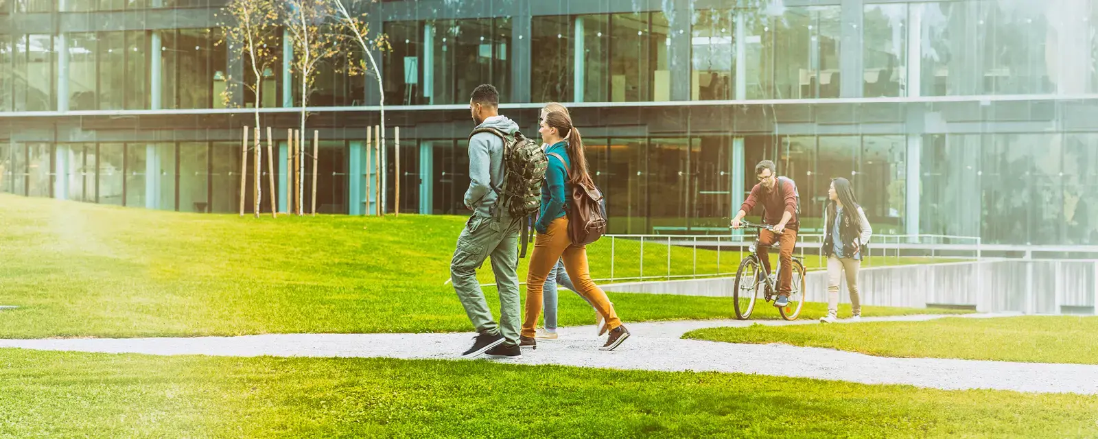 Two students with backpacks walking on a campus sidewalk.