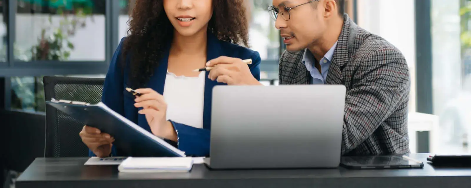 A woman and a man working at a desk in front of a laptop, reviewing the legislative details of the LOAN Act.