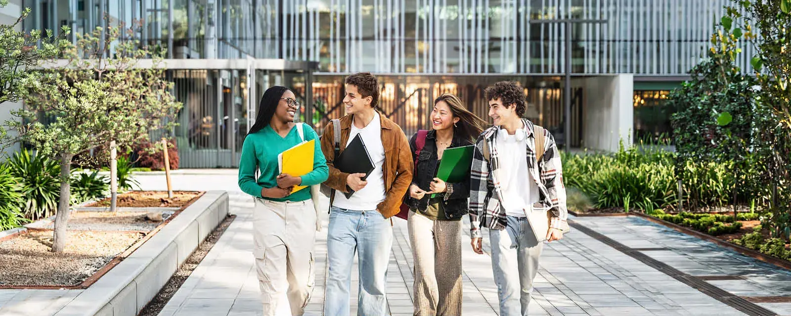 A diverse group of four students chatting as they walk across campus.