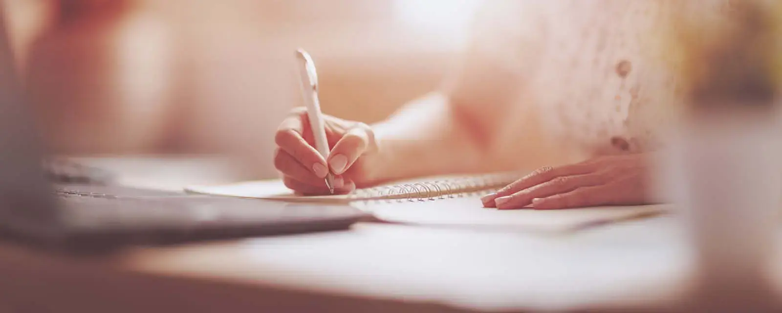 Woman writing in notebook at the office. Close-up panoramic view. Concept of the freelancer and of doing business at home.