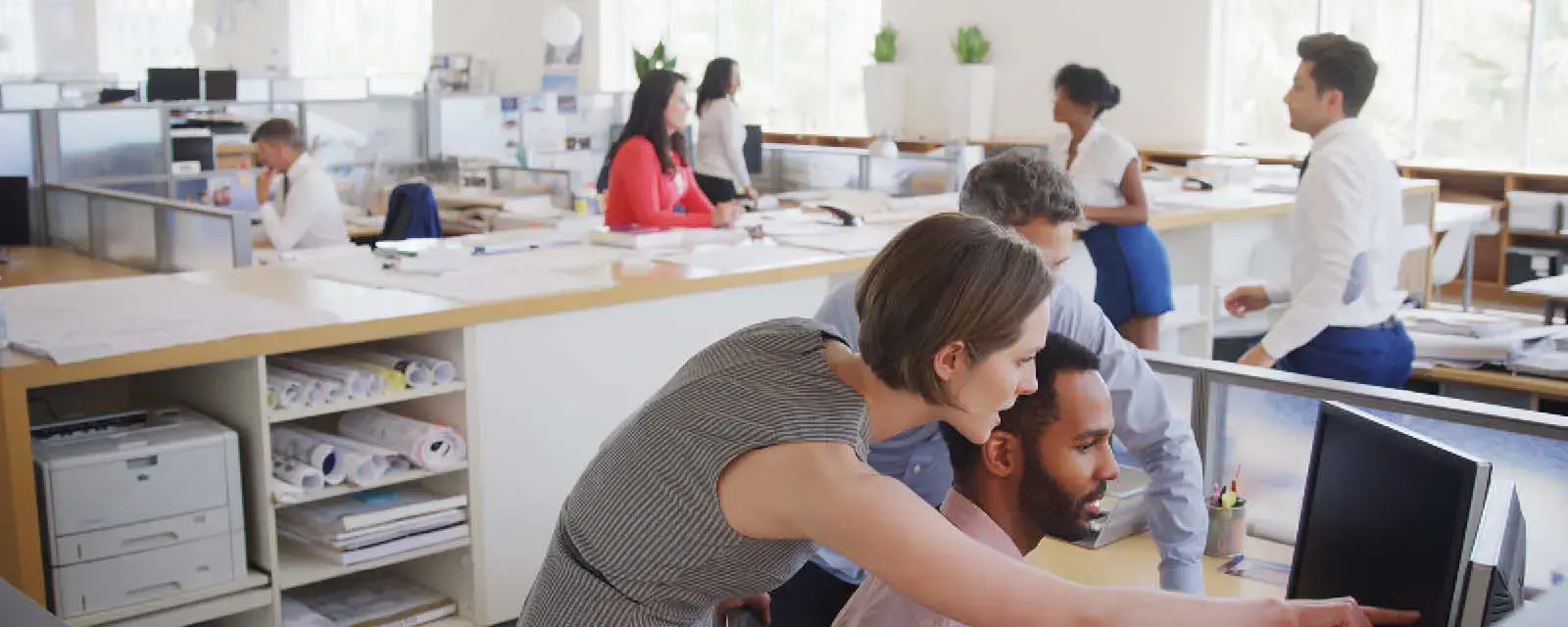 Multi-Cultural Business Team Meeting Around Desk In Modern Open Plan Architects Office Together