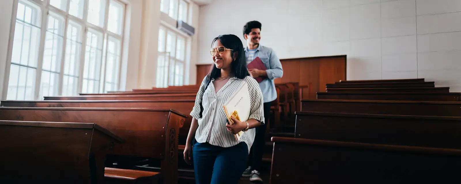 Student walking down stairs in a lecture hall.