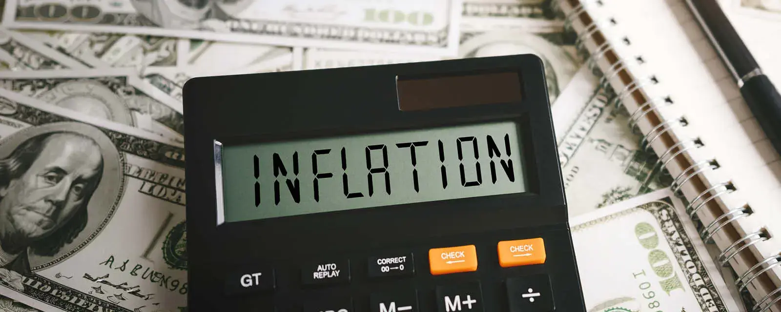 Calculator on top of money bills with the word inflation on the screen