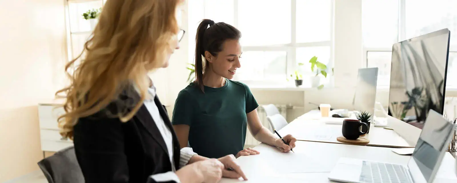 Student standing at a table, signing  a form.