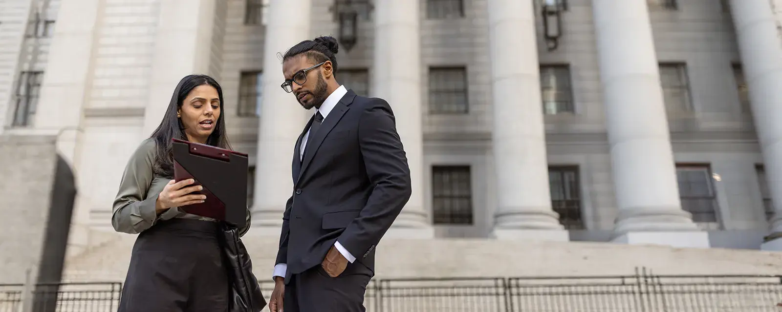Two attorneys discuss a case outside of a court house 