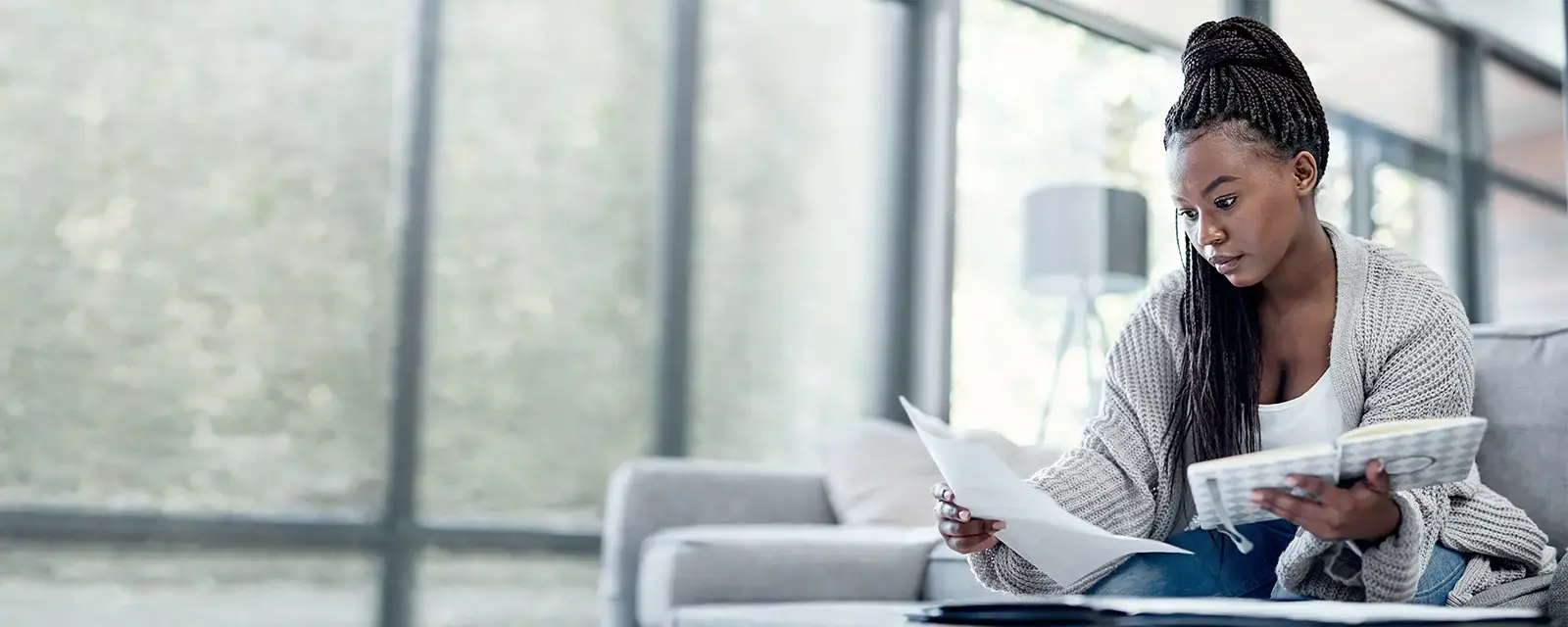  Shot of a young woman going over paperwork on the sofa at home.