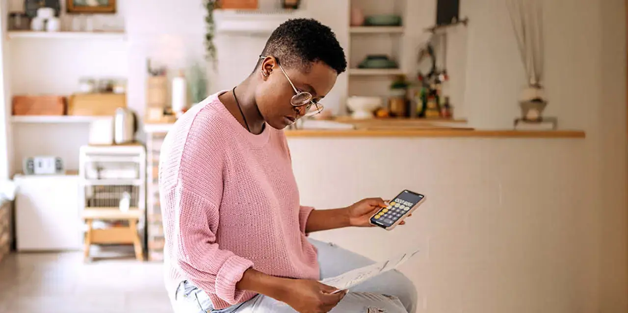 Young women holding a calculator and looking down at papers