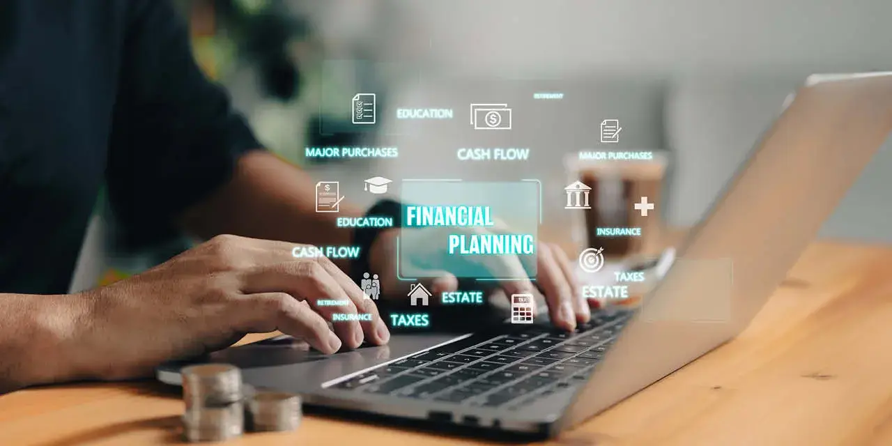 Hands on a laptop keyboard with financial related words floating above