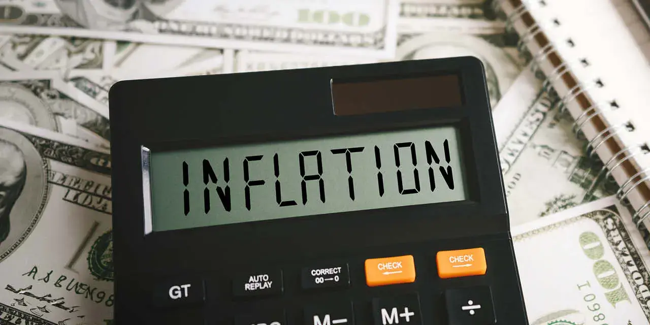 Calculator on top of money bills with the word inflation on the screen