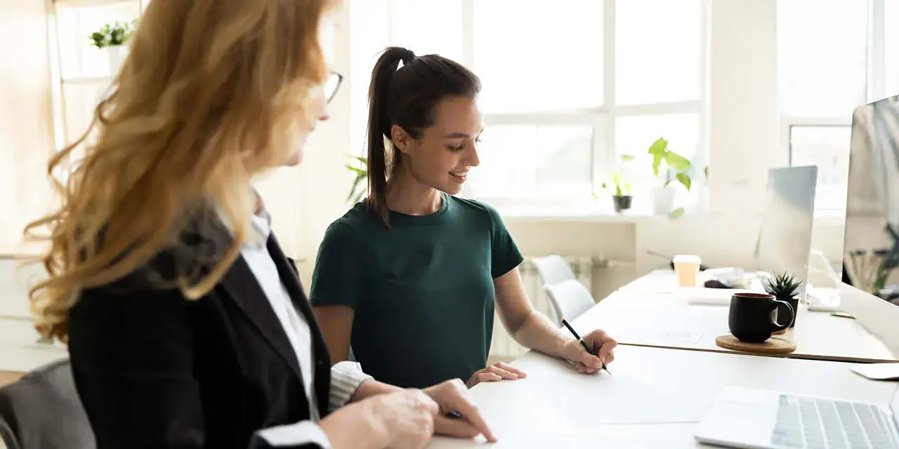 Student standing at a table, signing  a form.