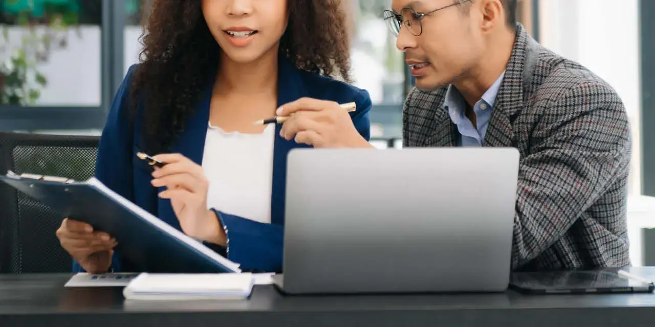 A woman and a man working at a desk in front of a laptop, reviewing the legislative details of the LOAN Act.