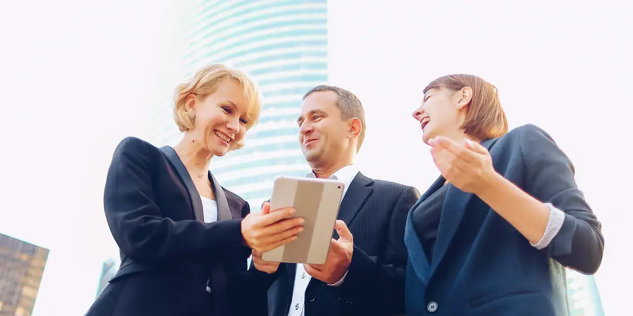 Satisfied business team members speaking outdoors in . Concept of biz partners enjoying successful result. Businesswomen talking with male boss and smiling.