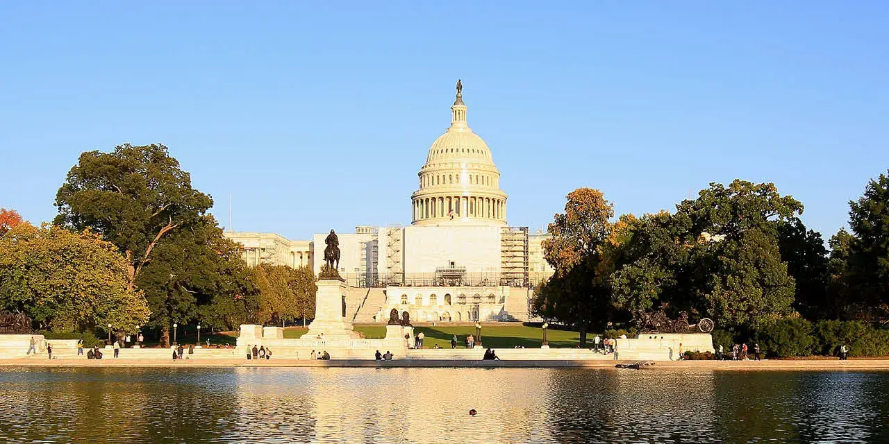 U.S. Capitol Building on a summer day with trees and a blue sky.