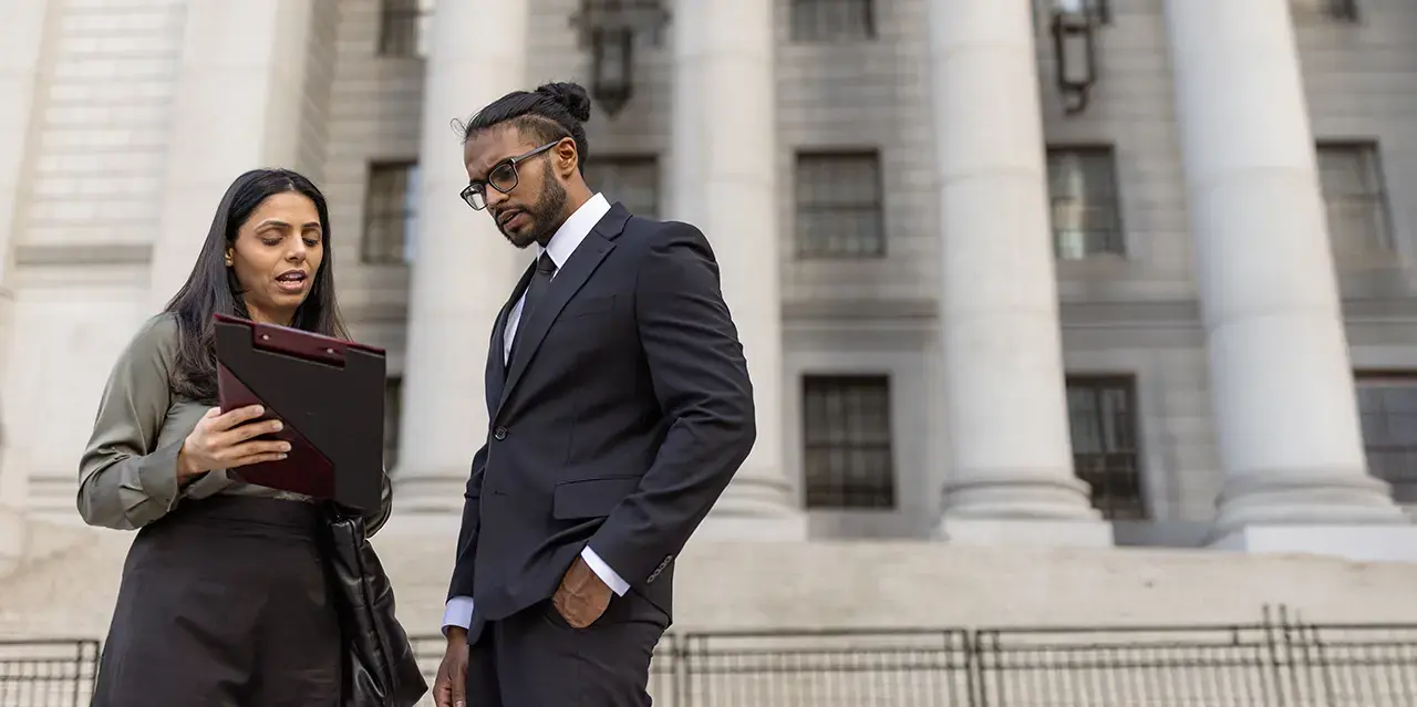 Two attorneys discuss a case outside of a court house 