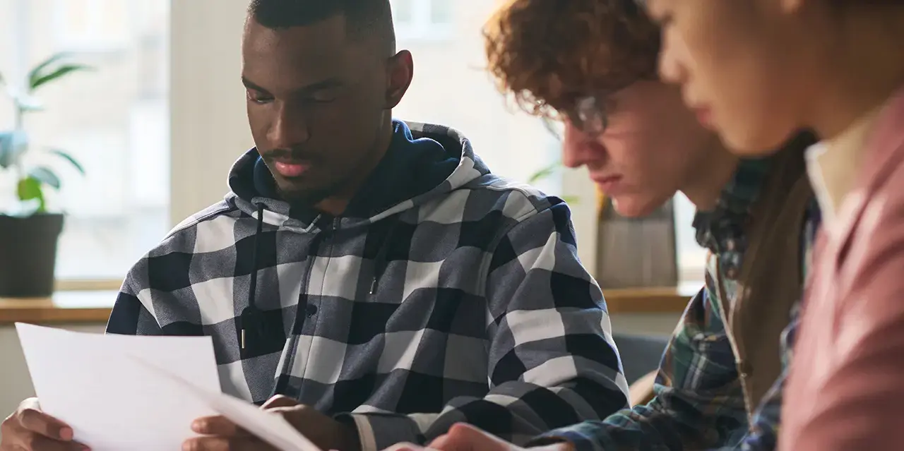 Diverse group of law school students studying together in classroom with focus and collaboration. They are sitting at a table with papers and documents.