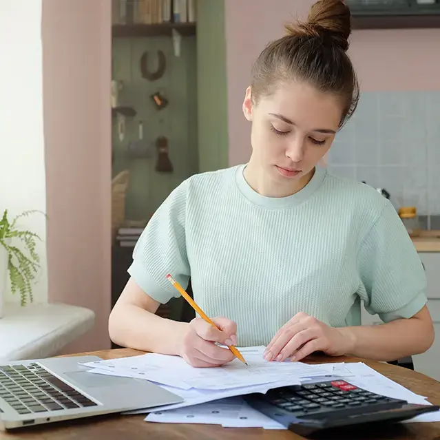 Portrait of young woman, sitting at kitchen table, filling out law school student loan application forms.
