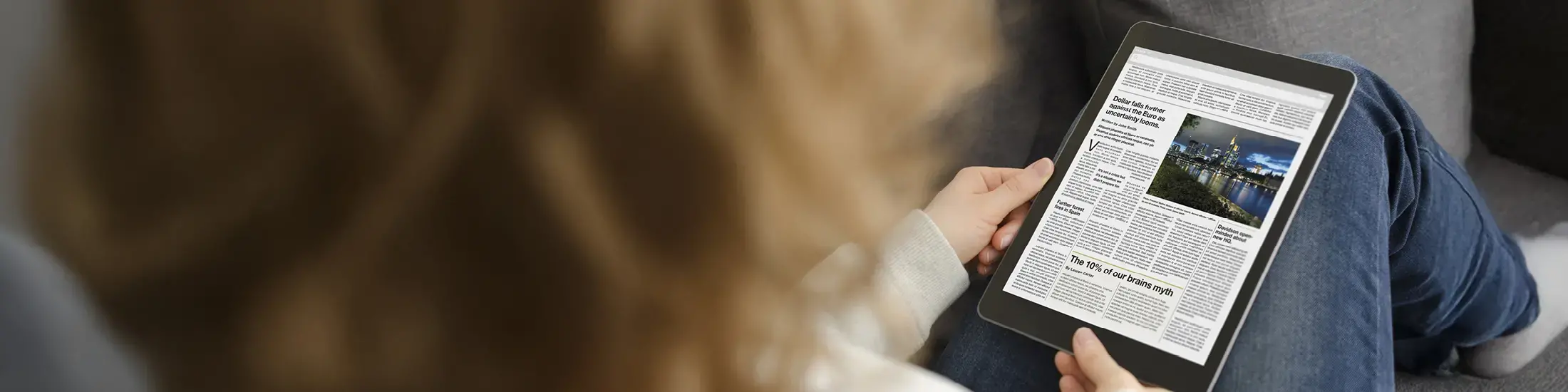 A person reading a newspaper on a tablet. 