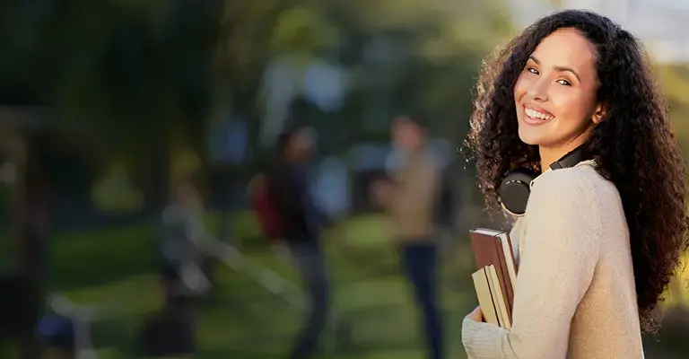 Portrait of an attractive young female student standing outside on campus. 