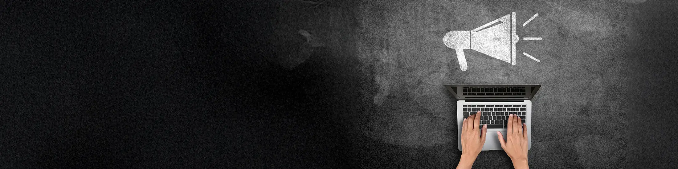 Hands on a laptop with megaphone icon on blackboard 