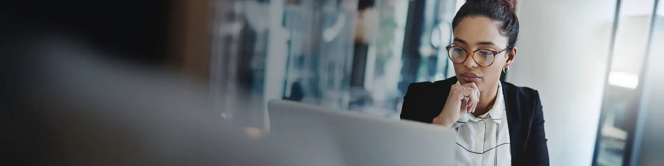 Businesswomen wearing glasses and reading a laptop screen. 