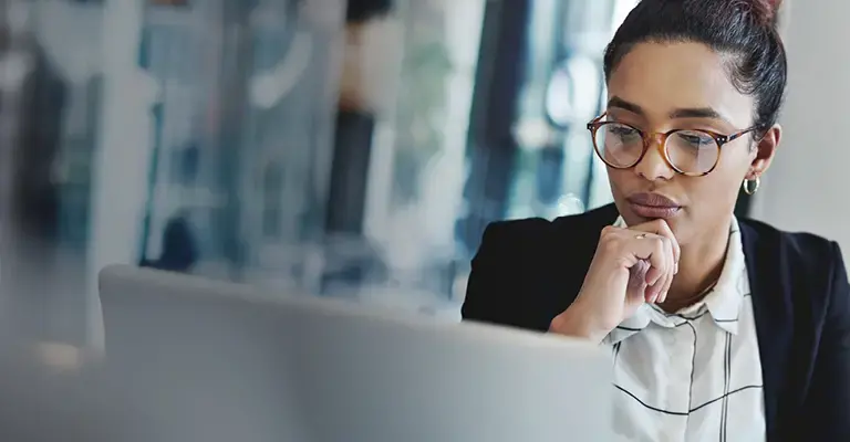 Businesswomen wearing glasses and reading a laptop screen. 