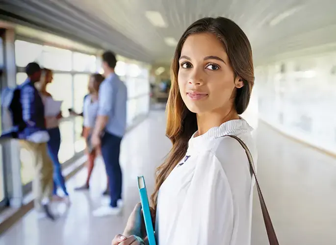 A female student walking the halls in college building with her books.