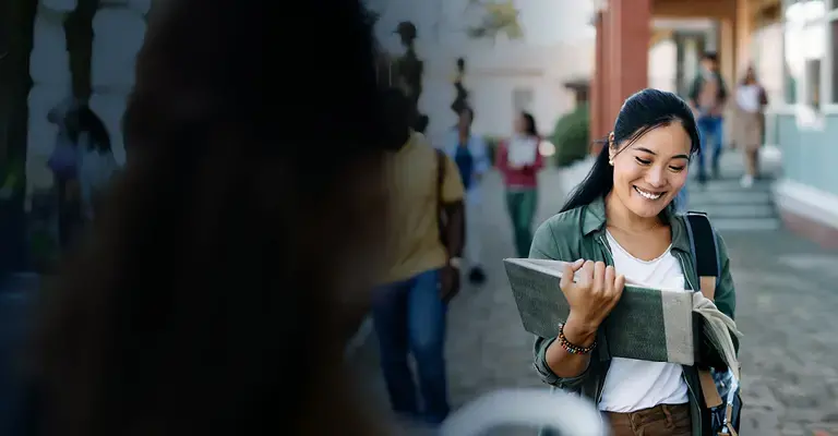 Happy Asian student communicating with her professor in front of university building.