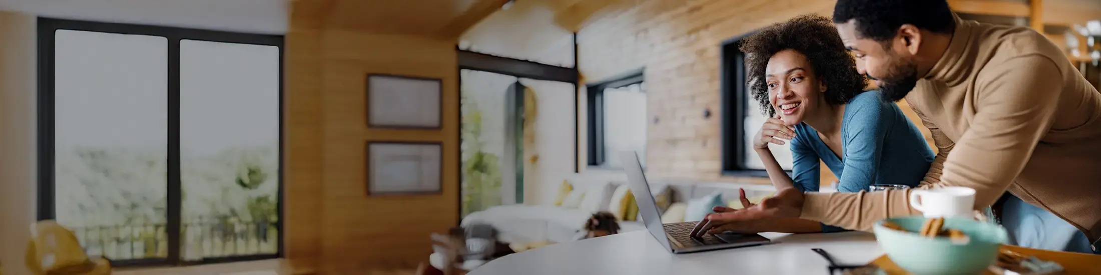 Happy black couple surfing the internet on a computer in the kitchen 