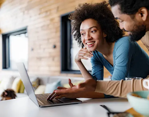 Happy black couple surfing the internet on a computer in the kitchen 