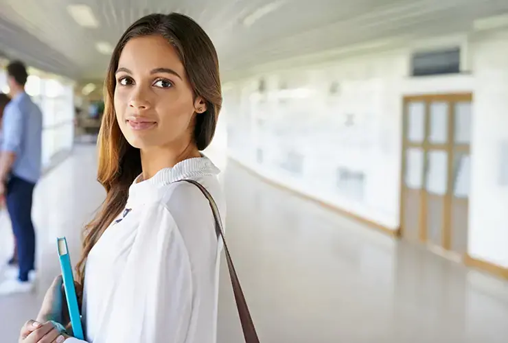 A female student walking the halls in college building with her books.