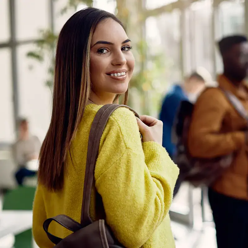 Happy female student at university hallway looking at camera.