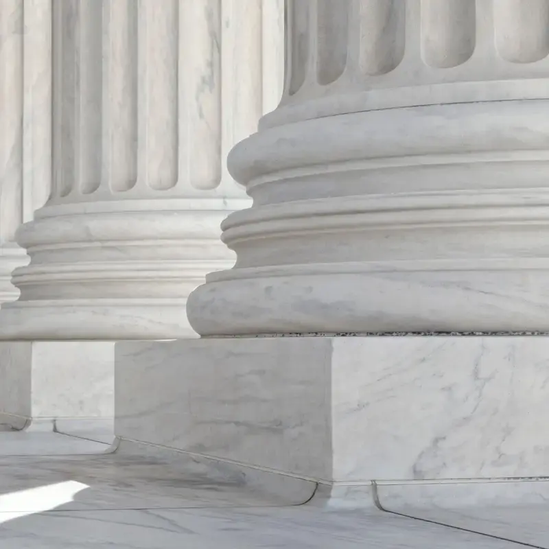 Close-up of the base and bottom of white marble columns.