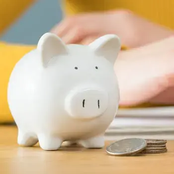White piggy bank with coins next to it