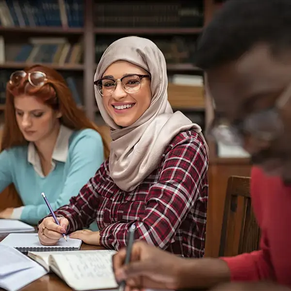 Three law students sitting at a table in a library taking notes