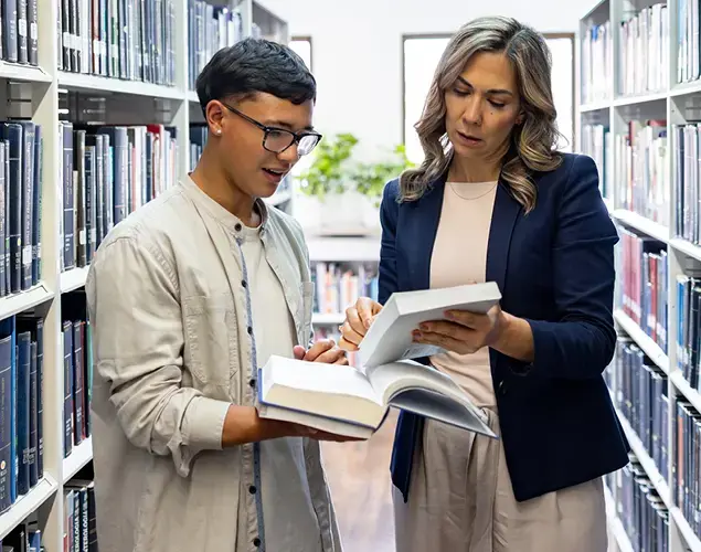 Law school student and faculty member reviewing materials in a library setting.